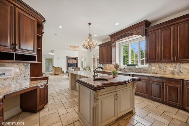 kitchen featuring stone tile flooring, tasteful backsplash, an island with sink, and open shelves