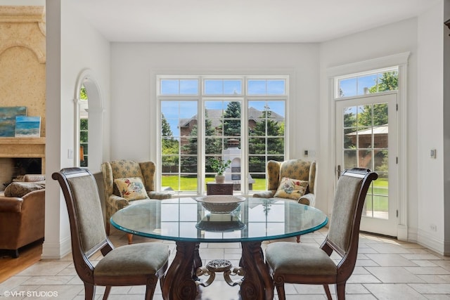 dining area featuring a fireplace, baseboards, and stone tile flooring