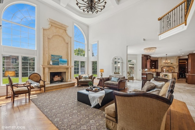 living room with a wealth of natural light, coffered ceiling, a high ceiling, an inviting chandelier, and a fireplace