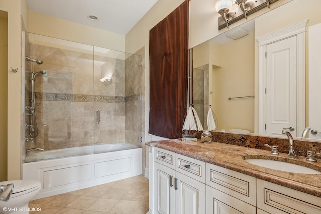 bathroom featuring tile patterned flooring, toilet, vanity, and bath / shower combo with glass door