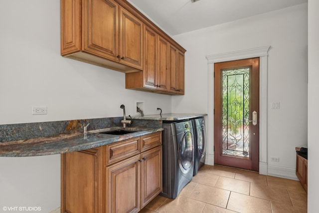 laundry area with a sink, washing machine and dryer, cabinet space, light tile patterned flooring, and baseboards