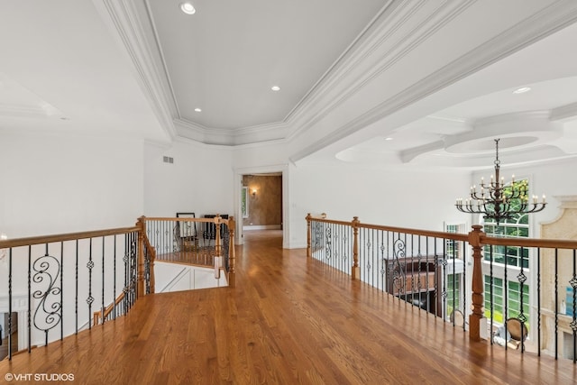 corridor with visible vents, an upstairs landing, wood finished floors, crown molding, and a chandelier