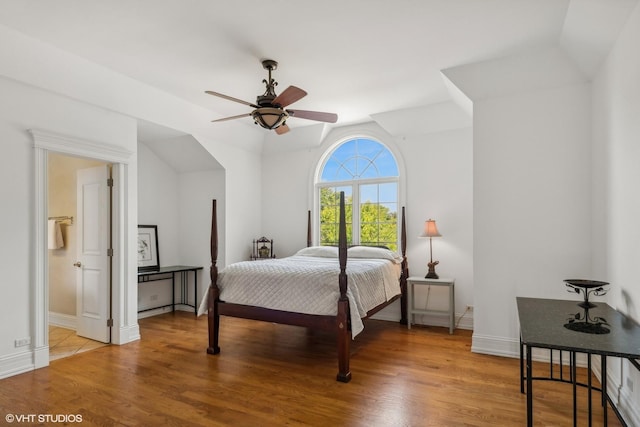 bedroom featuring lofted ceiling, baseboards, and light wood finished floors