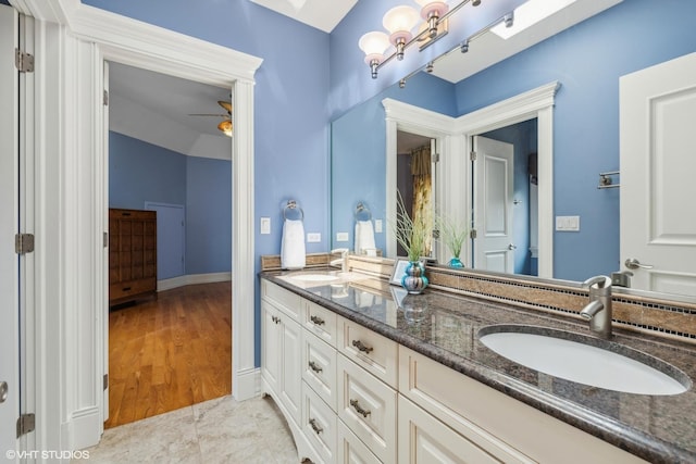 full bath with a sink, baseboards, ceiling fan, and double vanity