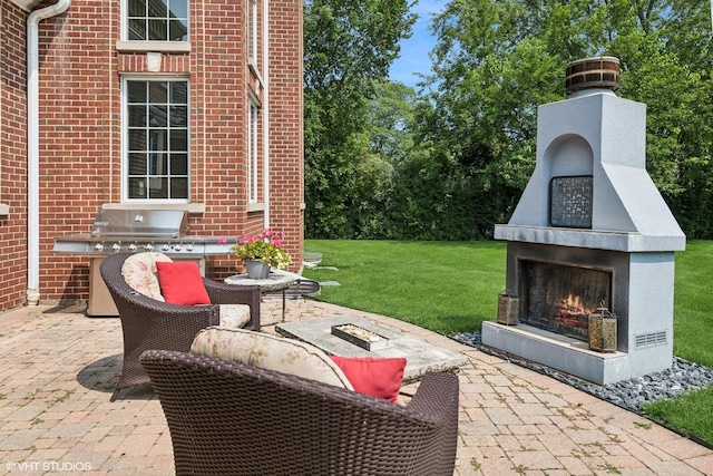 view of patio / terrace featuring a lit fireplace and a grill