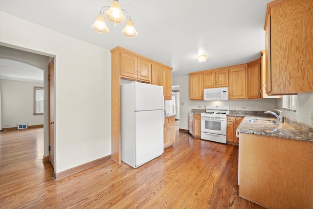 kitchen with white appliances, sink, light hardwood / wood-style flooring, dark stone countertops, and decorative light fixtures