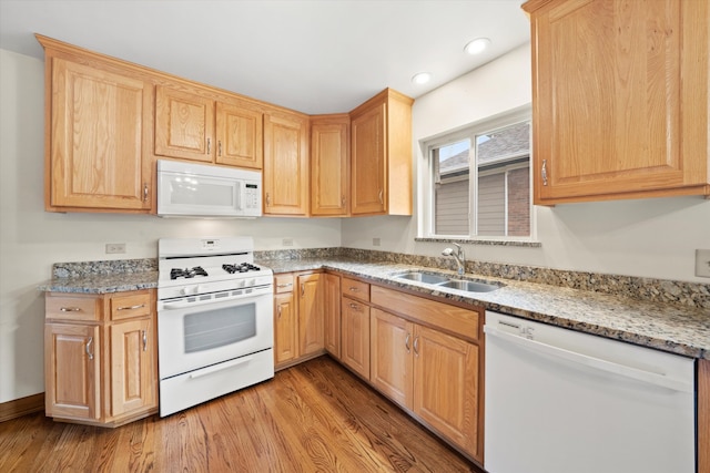 kitchen featuring light stone countertops, sink, light brown cabinets, light hardwood / wood-style floors, and white appliances