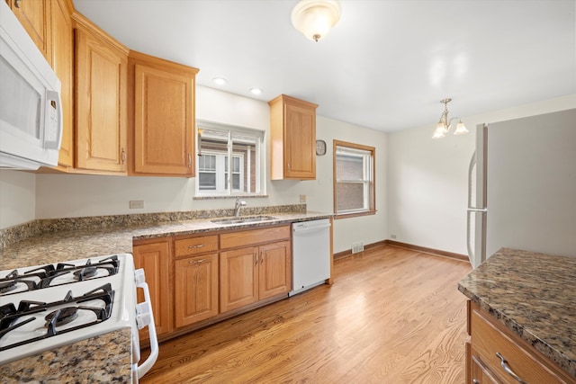 kitchen with pendant lighting, white appliances, sink, light hardwood / wood-style flooring, and a chandelier