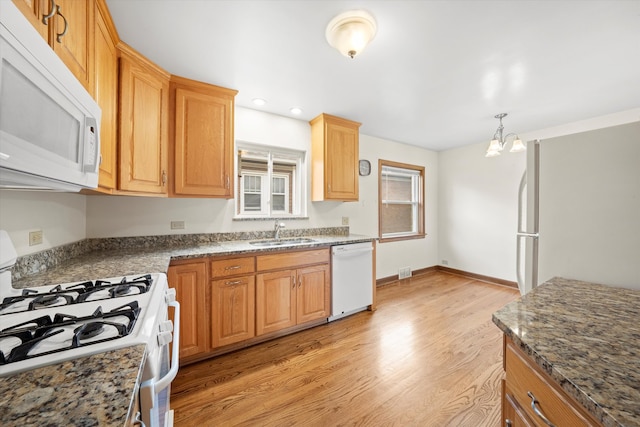 kitchen with white appliances, sink, light hardwood / wood-style flooring, a notable chandelier, and hanging light fixtures