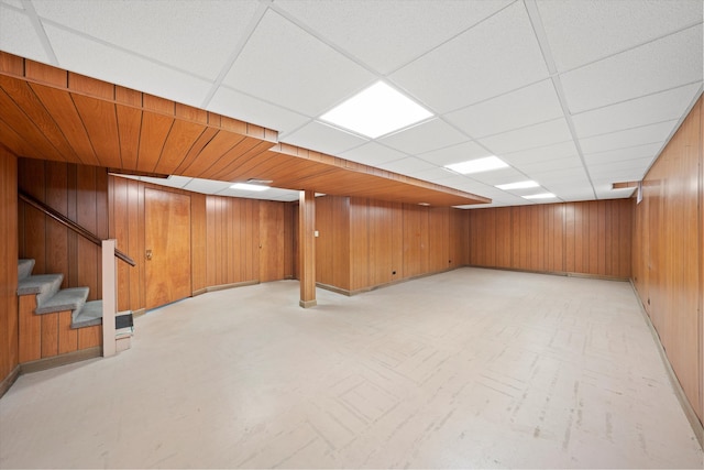 basement with a paneled ceiling and wooden walls