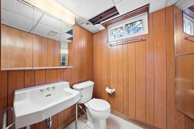 bathroom featuring tile patterned flooring, toilet, sink, and wooden walls