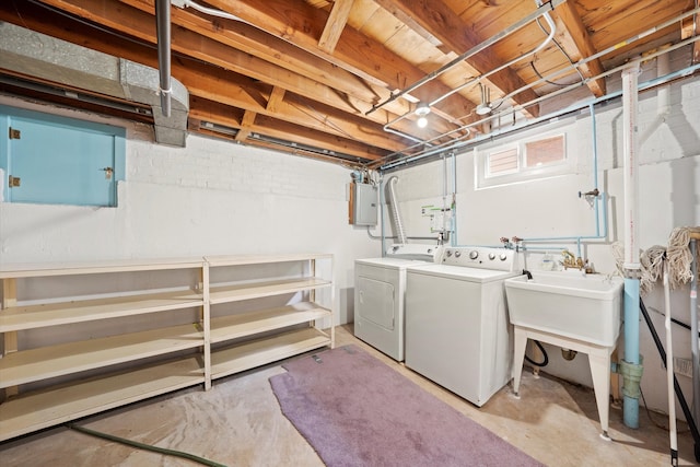 clothes washing area with washing machine and dryer, electric panel, and sink