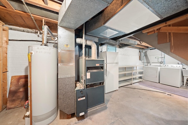 basement featuring white refrigerator, gas water heater, and washing machine and dryer