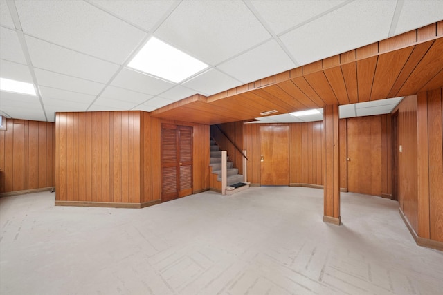 basement with a paneled ceiling and wood walls