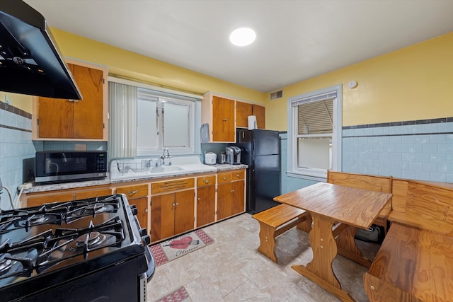 kitchen featuring backsplash, extractor fan, sink, black appliances, and light tile patterned floors