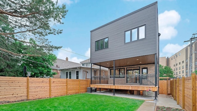 rear view of house featuring central air condition unit, a wooden deck, and a yard