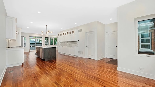 kitchen featuring pendant lighting, white cabinetry, a kitchen island with sink, and light hardwood / wood-style flooring