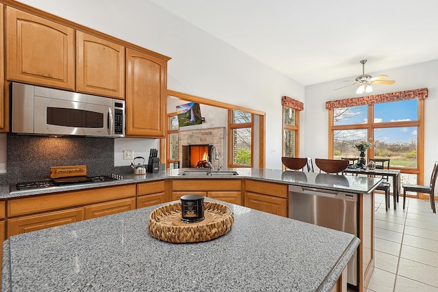 kitchen with sink, ceiling fan, appliances with stainless steel finishes, backsplash, and a kitchen island