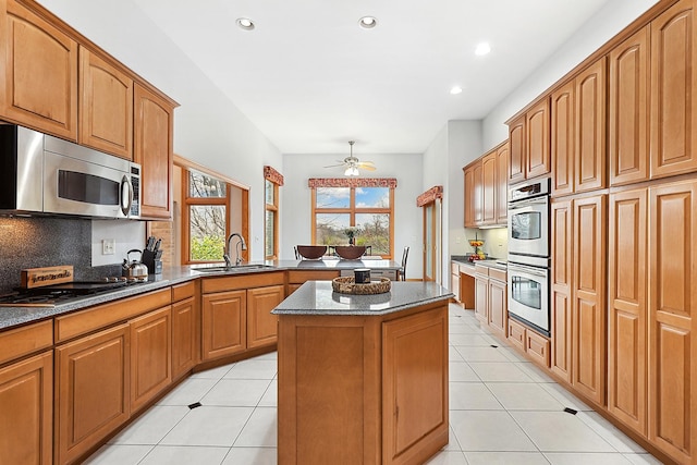 kitchen with sink, light tile patterned floors, stainless steel appliances, a kitchen island, and decorative backsplash