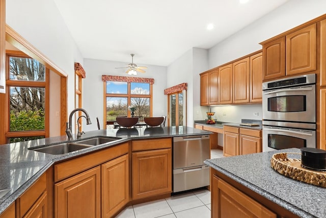 kitchen featuring sink, light tile patterned floors, ceiling fan, dark stone countertops, and double oven