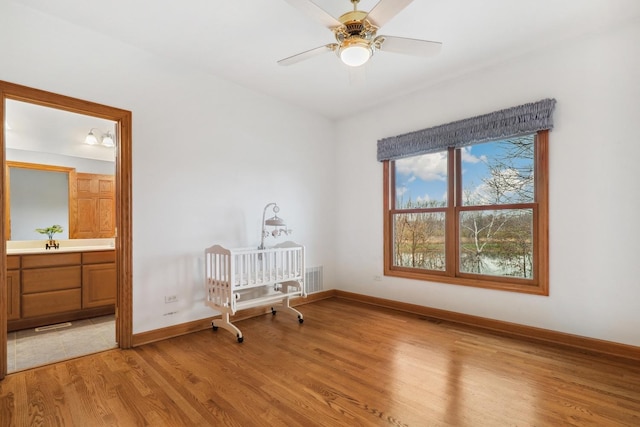 bedroom featuring ensuite bathroom, sink, ceiling fan, and light wood-type flooring