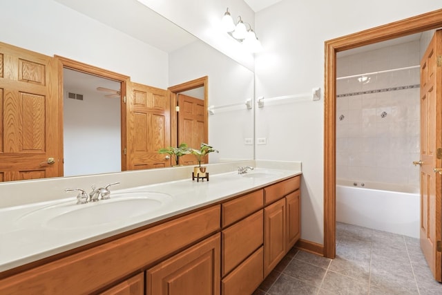 bathroom with tile patterned flooring, vanity, and tiled shower / bath