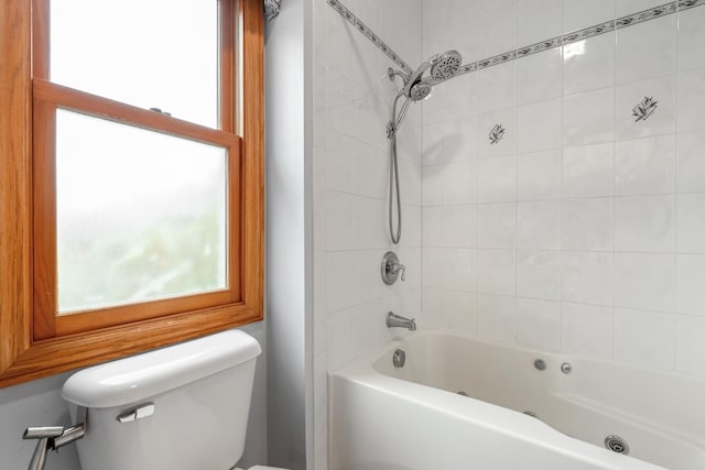 bathroom featuring tiled shower / bath combo and toilet