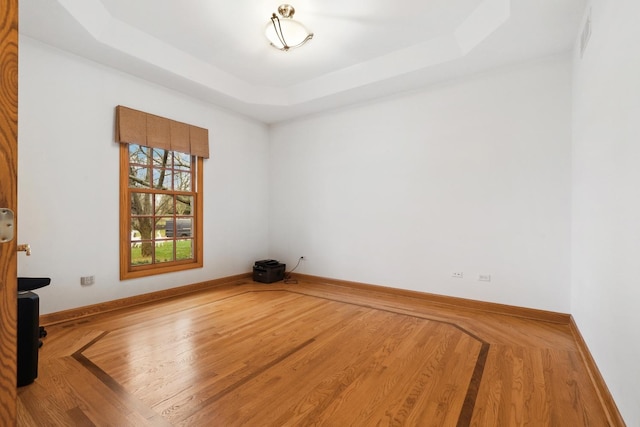 spare room with a raised ceiling and hardwood / wood-style flooring