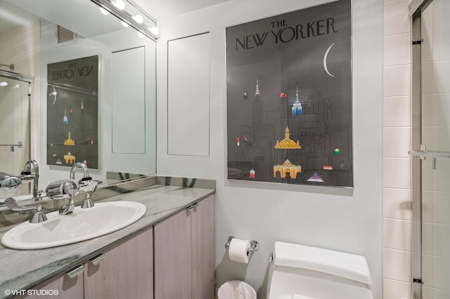 bathroom featuring vanity, an enclosed shower, and toilet