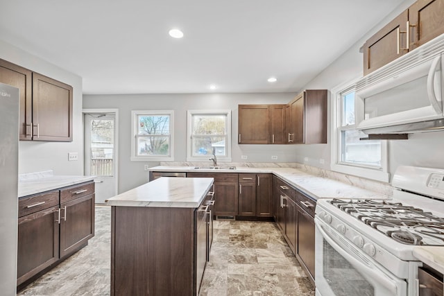 kitchen with a kitchen island, dark brown cabinetry, white appliances, and sink