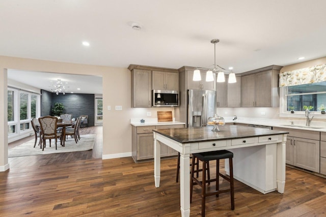 kitchen with sink, stainless steel appliances, a center island, decorative light fixtures, and a chandelier