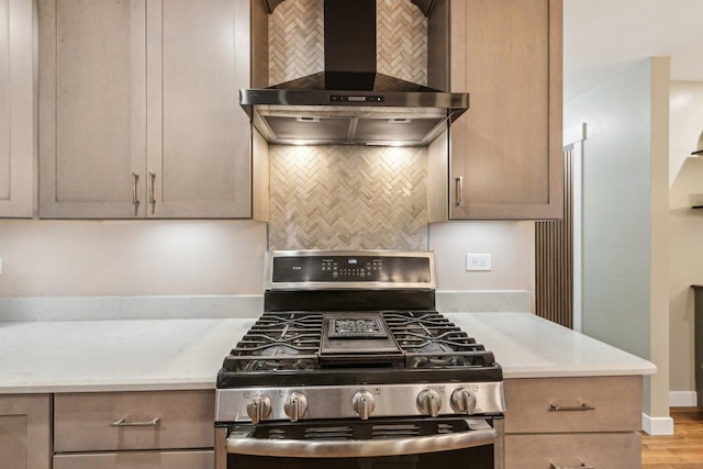 kitchen featuring wall chimney range hood, tasteful backsplash, stainless steel range with gas stovetop, and light wood-type flooring