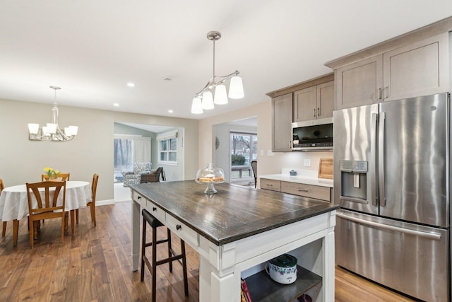 kitchen with hardwood / wood-style flooring, appliances with stainless steel finishes, decorative light fixtures, and a center island