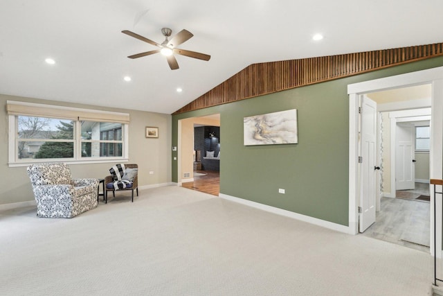 living area with vaulted ceiling, light colored carpet, and ceiling fan