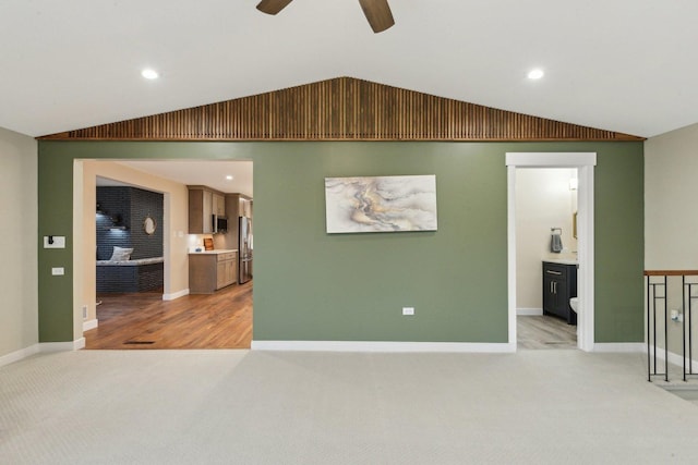 unfurnished living room with vaulted ceiling, light colored carpet, and ceiling fan