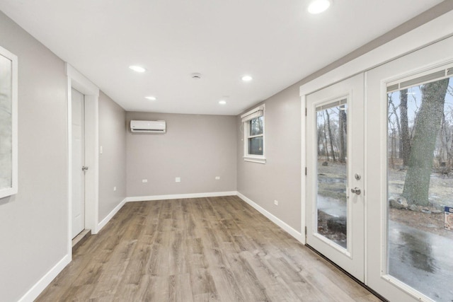 empty room featuring light hardwood / wood-style floors, french doors, and a wall mounted AC