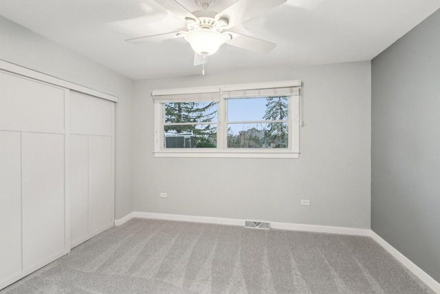 unfurnished bedroom featuring ceiling fan, light colored carpet, and a closet