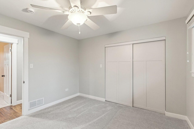 unfurnished bedroom featuring ceiling fan, light colored carpet, and a closet