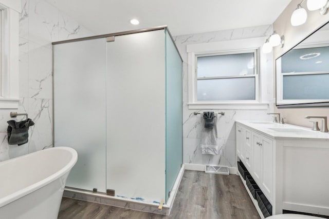 bathroom featuring vanity, independent shower and bath, hardwood / wood-style floors, and tile walls