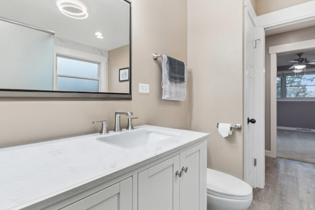 bathroom featuring ceiling fan, vanity, toilet, and hardwood / wood-style floors