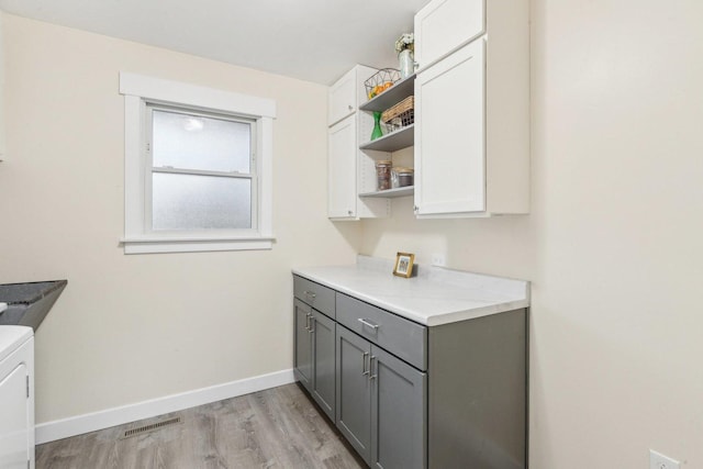 laundry area with cabinets and light hardwood / wood-style flooring