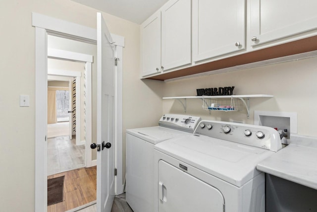 laundry area featuring cabinets, washer and dryer, and light wood-type flooring