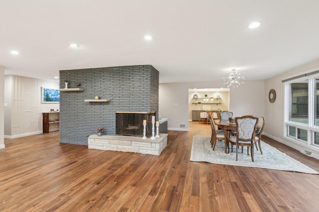 dining area featuring wood-type flooring and a brick fireplace