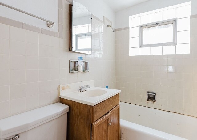 full bathroom featuring vanity, toilet, a wealth of natural light, and tile walls