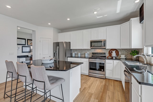 kitchen featuring a center island, light wood-type flooring, stainless steel appliances, and white cabinetry