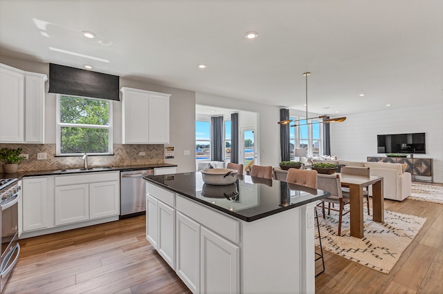 kitchen with white cabinets, sink, light hardwood / wood-style flooring, appliances with stainless steel finishes, and a kitchen island