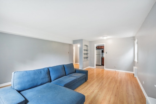 living room featuring light wood-type flooring and built in features