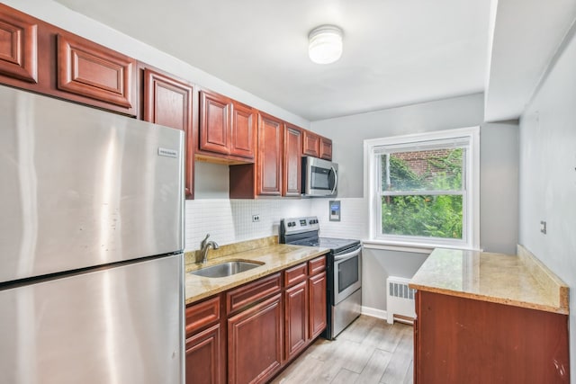 kitchen featuring light stone countertops, appliances with stainless steel finishes, radiator heating unit, and sink