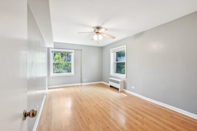 unfurnished room featuring light hardwood / wood-style flooring, radiator, a healthy amount of sunlight, and ceiling fan