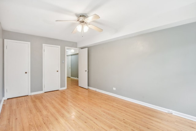 unfurnished bedroom featuring multiple closets, ceiling fan, and light wood-type flooring